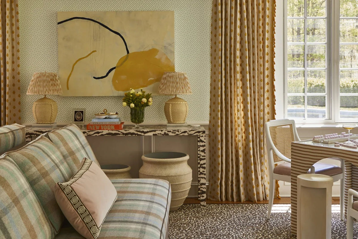 Pleated patterned lampshades on rattan lamps in a room layered with leopard, plaid, and stripe