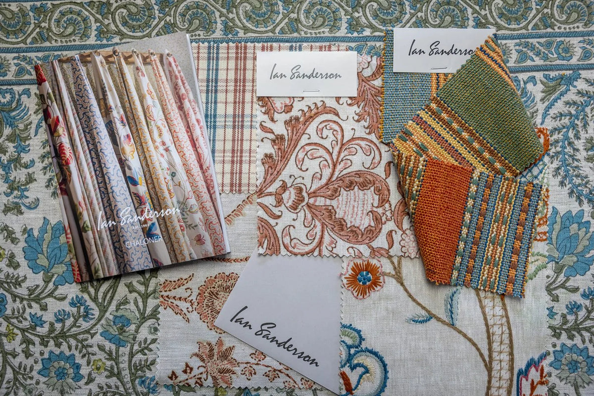 Ian Sanderson swatch cards in stripe, check, and floral laid over a length of patterned cloth