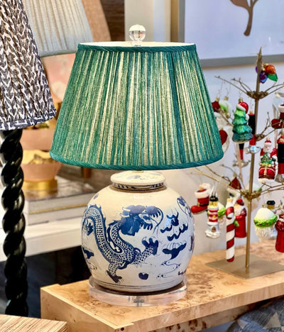 Luxury green Fermoie pleated empire lampshade displayed on a blue and white ginger jar lamp, offering a classic and timeless look for sophisticated interiors.