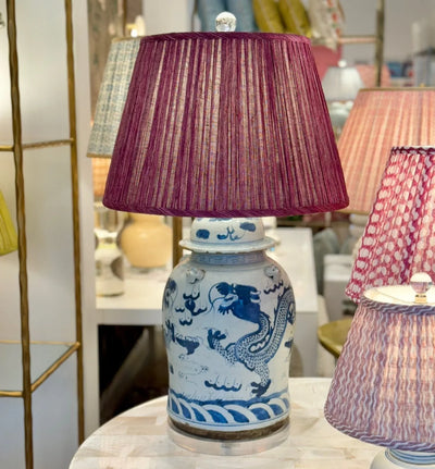 Luxury Fermoie Back to the Fuchsia pleated empire lampshades in deep pink, displayed on an elegant blue and white ginger jar lamp. 