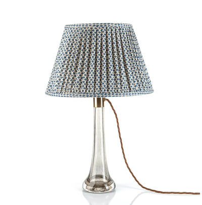 Luxury designer gathered empire lampshade in Fermoie Blue Marden fabric displayed on a clear glass lamp