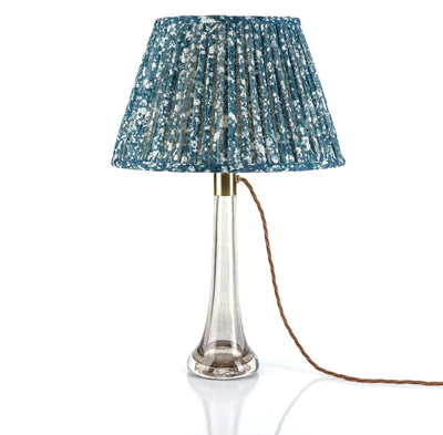 Luxury Fermoie Blue Quartz fabric with a speckled blue and white pattern, showing designer pleated detailing displayed on a clear glass lamp.