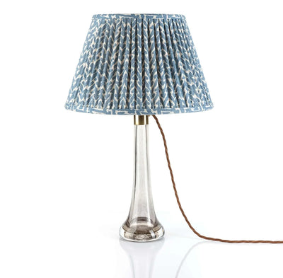Luxury designer Fermoie Blue Rabanna gathered empire lampshade with pleated detailing displayed on a clear glass lamp base.