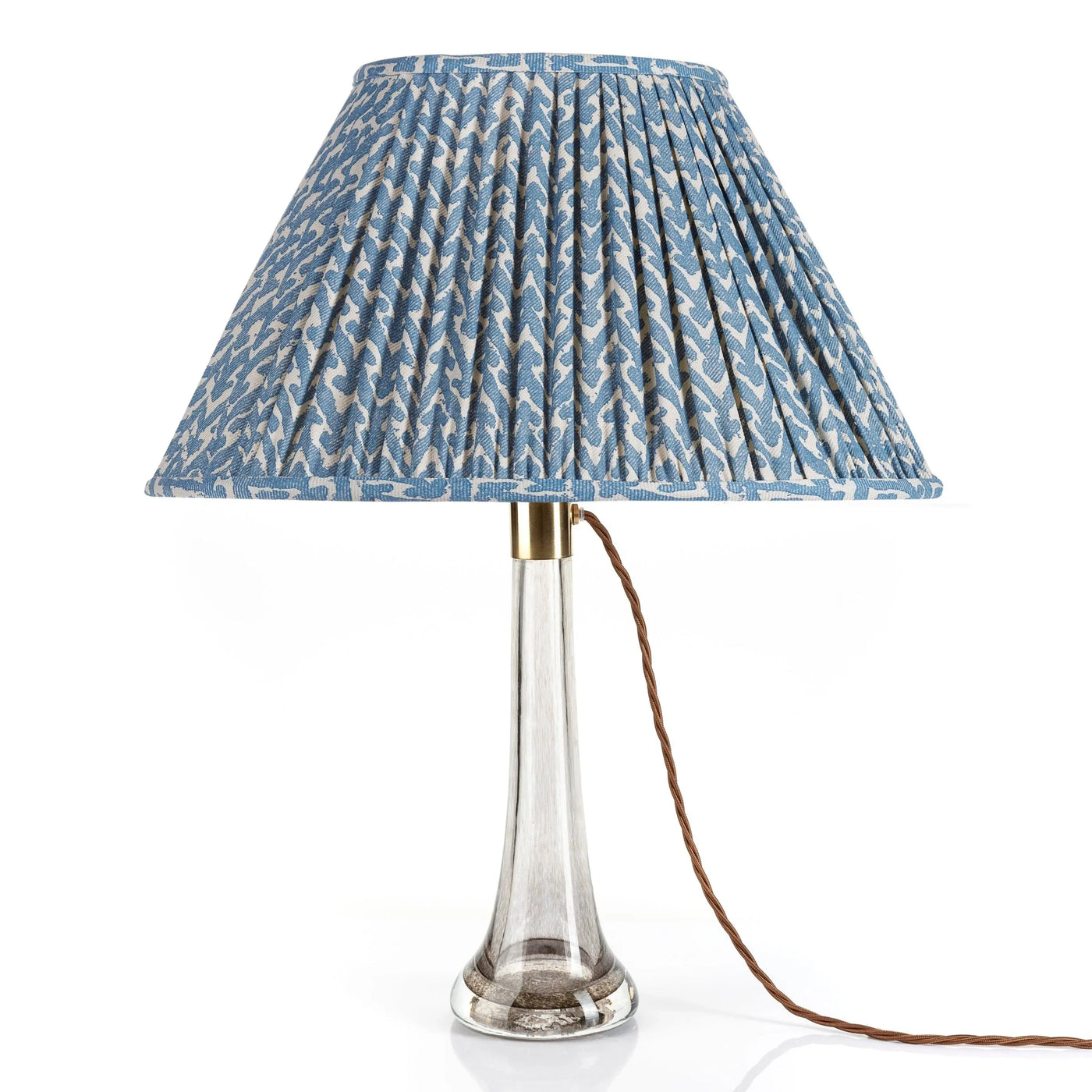 Front view of designer Fermoie Blue Rabanna gathered empire oval lampshade with pleated detailing displayed on a clear glass lamp base.