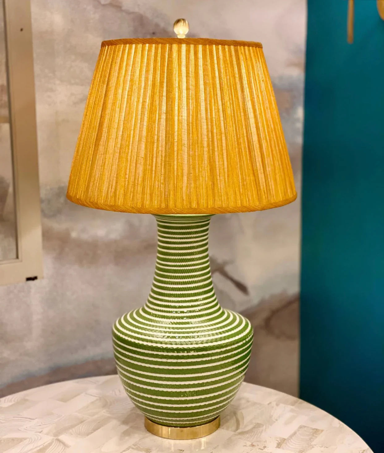 Luxury designer Fermoie gathered empire lampshade in golden yellow fabric with pleated detailing displayed on a green lamp