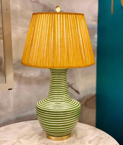 Luxury designer Fermoie gathered empire lampshade in golden yellow fabric with pleated detailing displayed on a green lamp