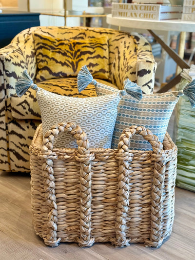 pair of Ian Sanderson Reel Stripe in Blue Stone and Nettie in Taupe Dove Cushions with Blue Tassels in a woven basket
