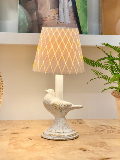 Decorative table lamp with a bird design on a wooden surface