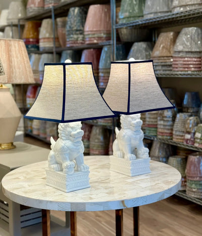 Oatmeal Linen Square Bell Lampshade with Navy Trim paired with Porcelain White Foo Dog Table Lamps