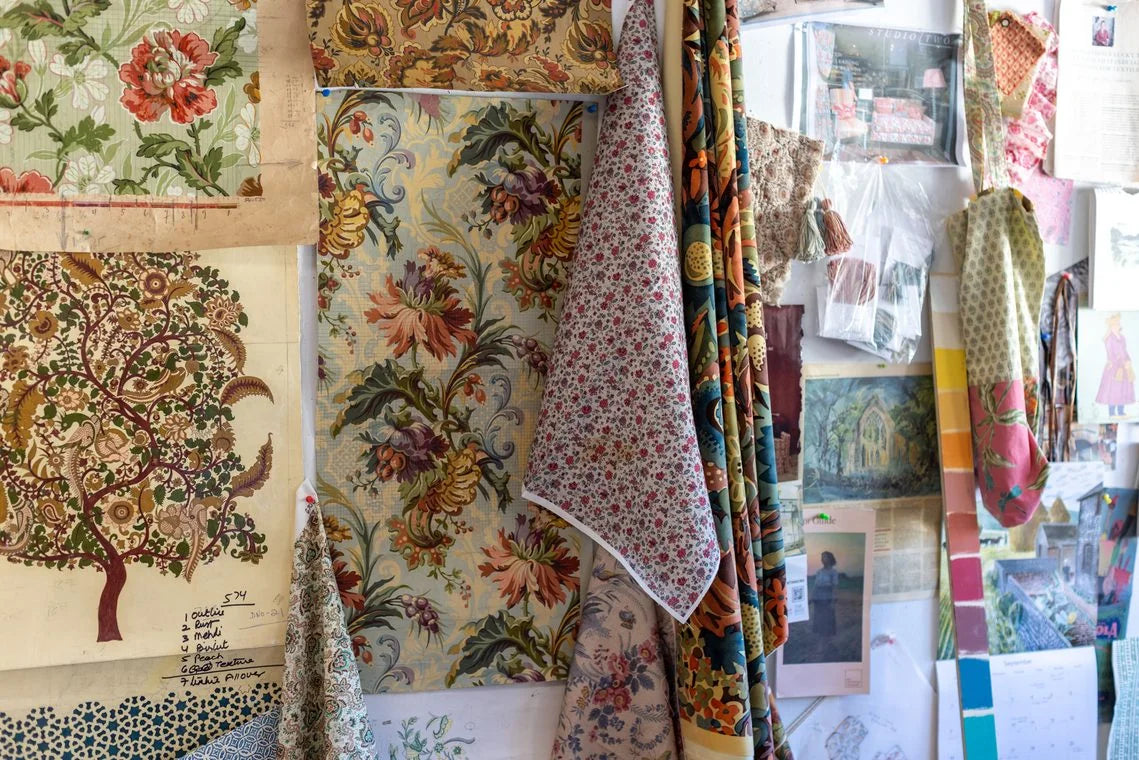 Vision boards of printed florals, drawings, and swatches pinned across the studio wall