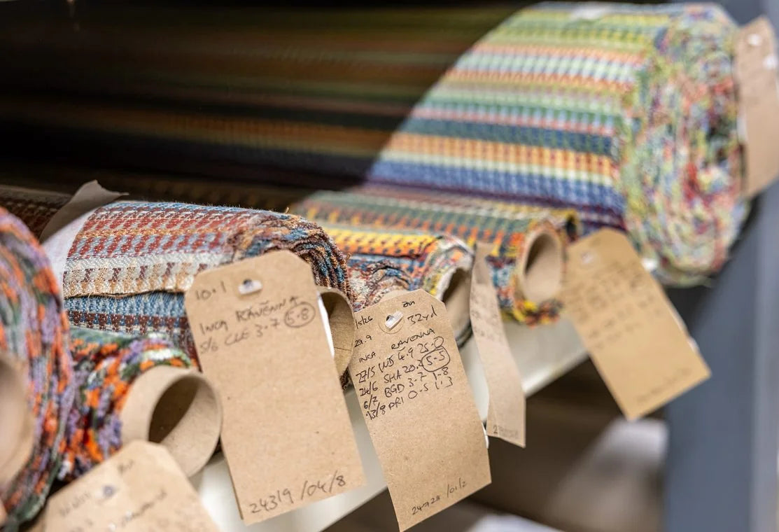 Rolls of woven fabric with handwritten tags tied to their ends