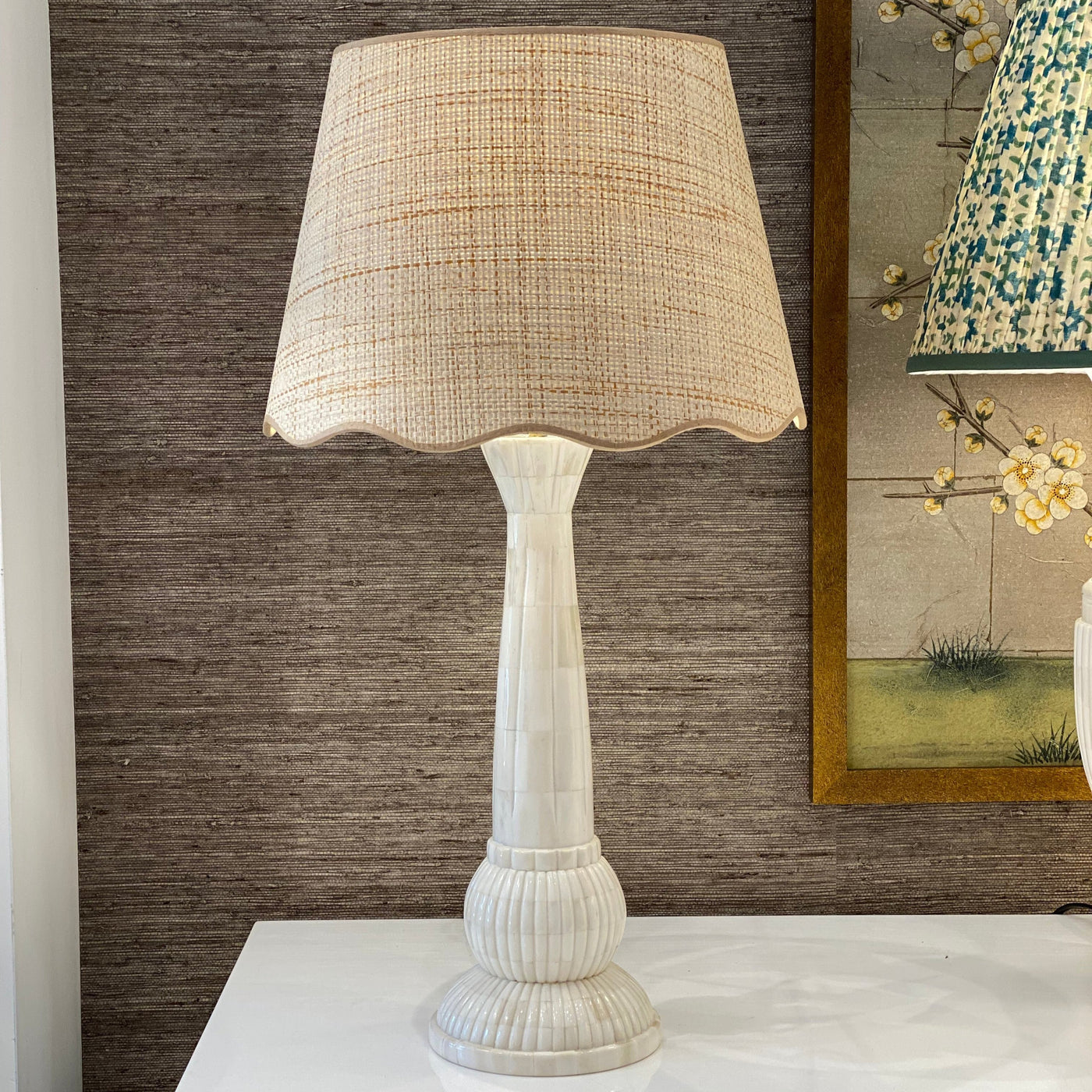 Scalloped raffia lampshade with beige trim on a bone lamp